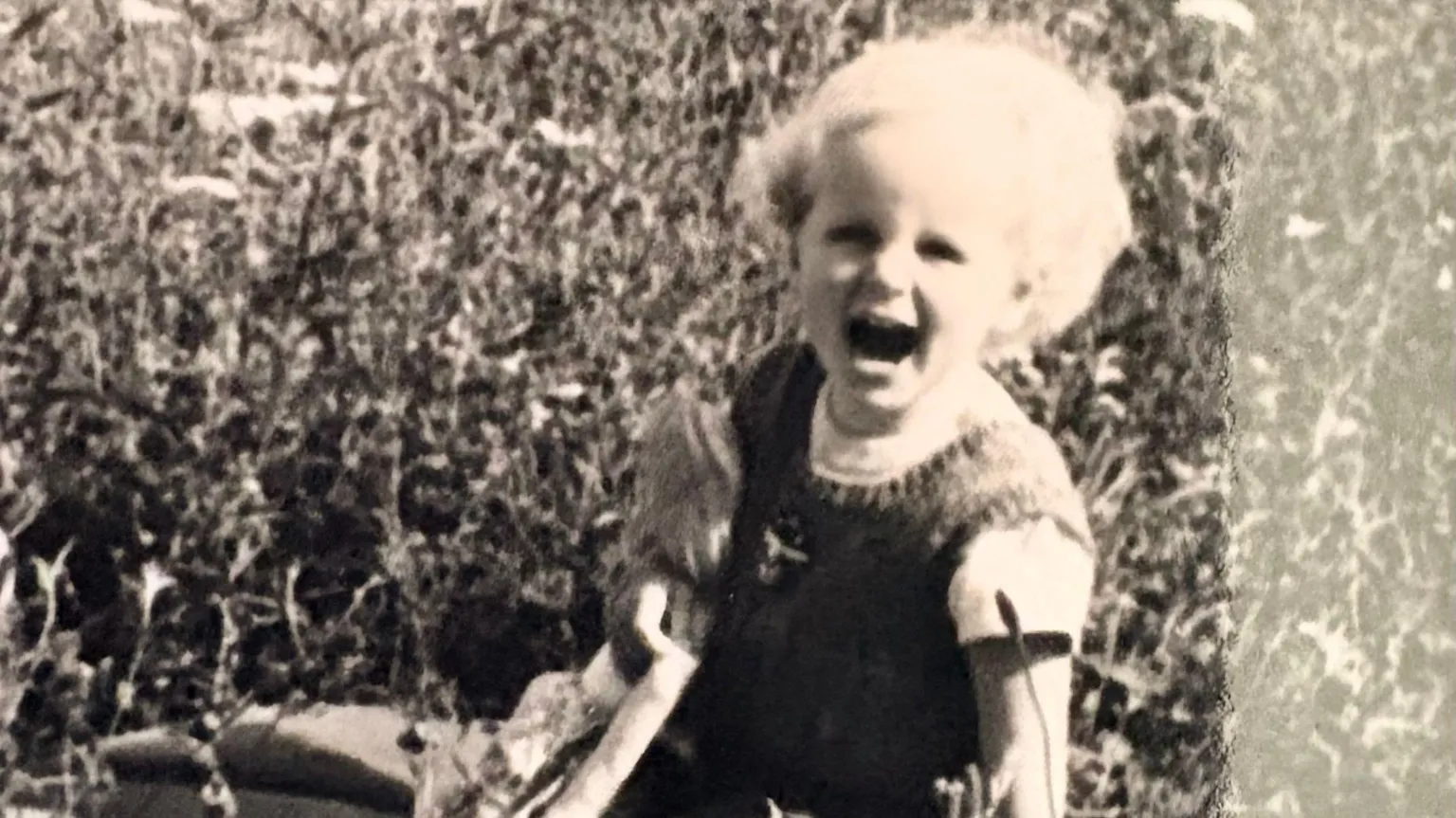 Maggie O'Farrell black and white photo of Maggie as a toddler blonde hair -- mouth open kneeling down on the ground rugged landscape of Ireland behind her