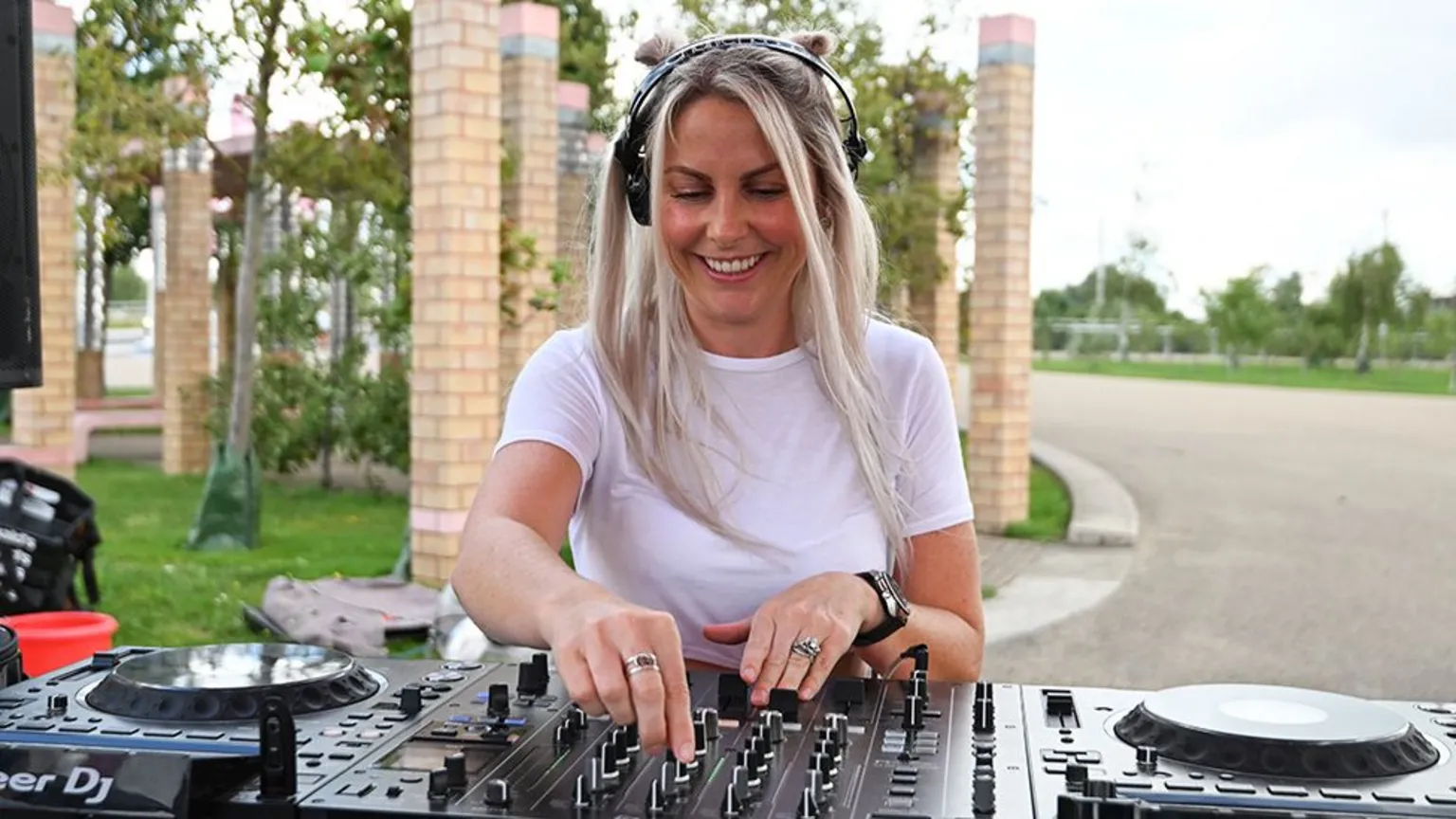Getty Images DJ Charlie Hedges, a female, wearing a white tshirt and headphones, as she DJs on black decks.